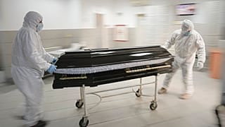 FILE - Funeral house employees drag a coffin on a trolley to take a COVID-19 victim for burial, in Bucharest, Romania, November 8, 2021.