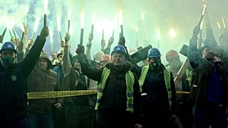 Coal miners hold flares as they gather during protest near government building in Sarajevo, on November 23, 2021.