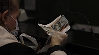 A woman changes Turkish lira for USD and Euro at a currency exchange shop, in Ankara, Turkey, Tuesday, Nov. 23, 2021.