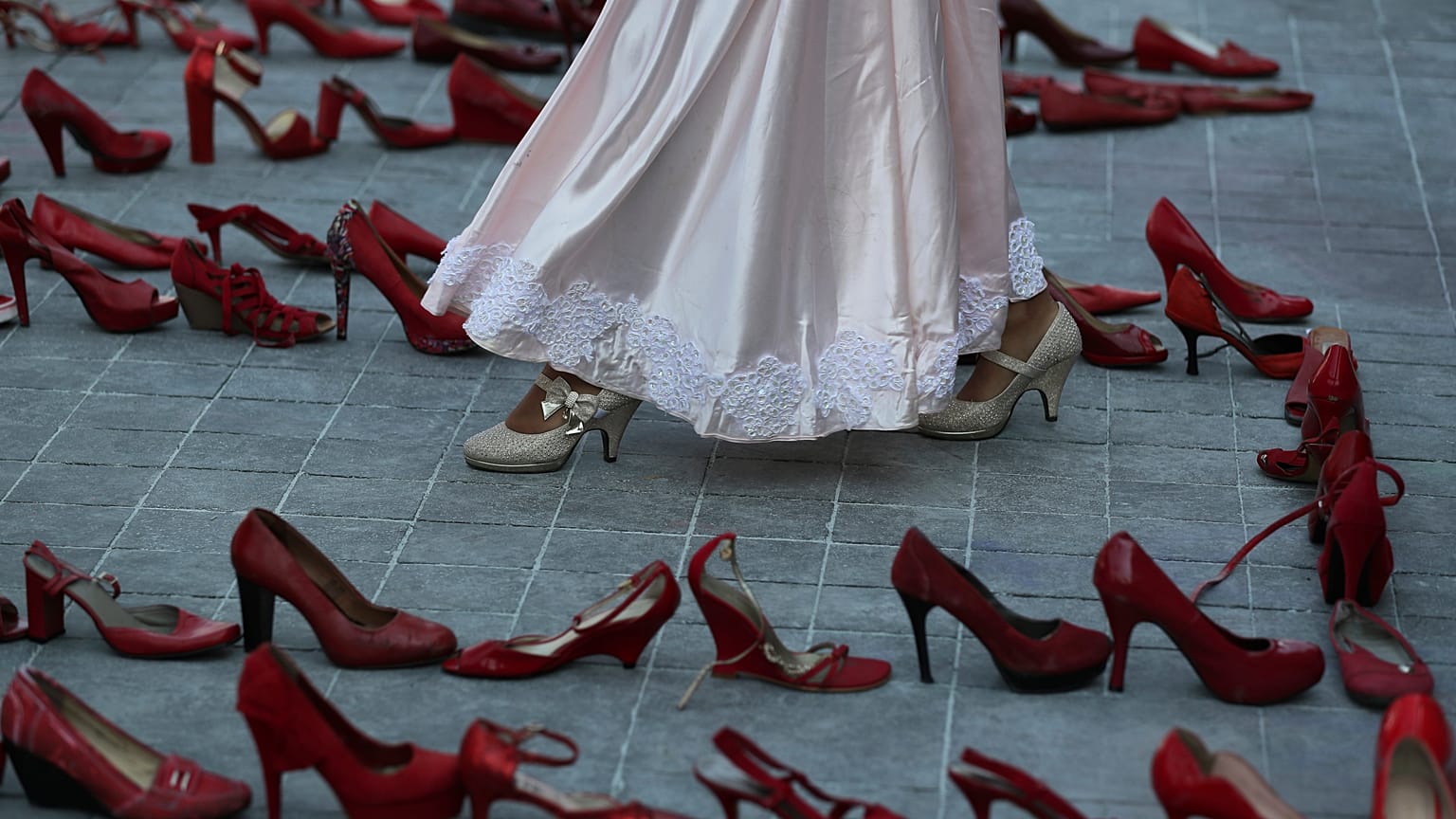 Una actriz camina cerca de una fila de zapatos rojos que representan a las mujeres asesinadas, 9/3/2020, Ciudad de México, México 