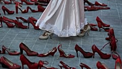 Una actriz camina cerca de una fila de zapatos rojos que representan a las mujeres asesinadas, 9/3/2020, Ciudad de México, México 