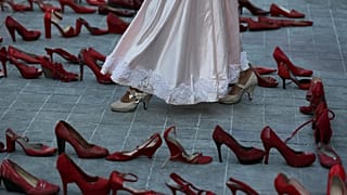 Una actriz camina cerca de una fila de zapatos rojos que representan a las mujeres asesinadas, 9/3/2020, Ciudad de México, México 
