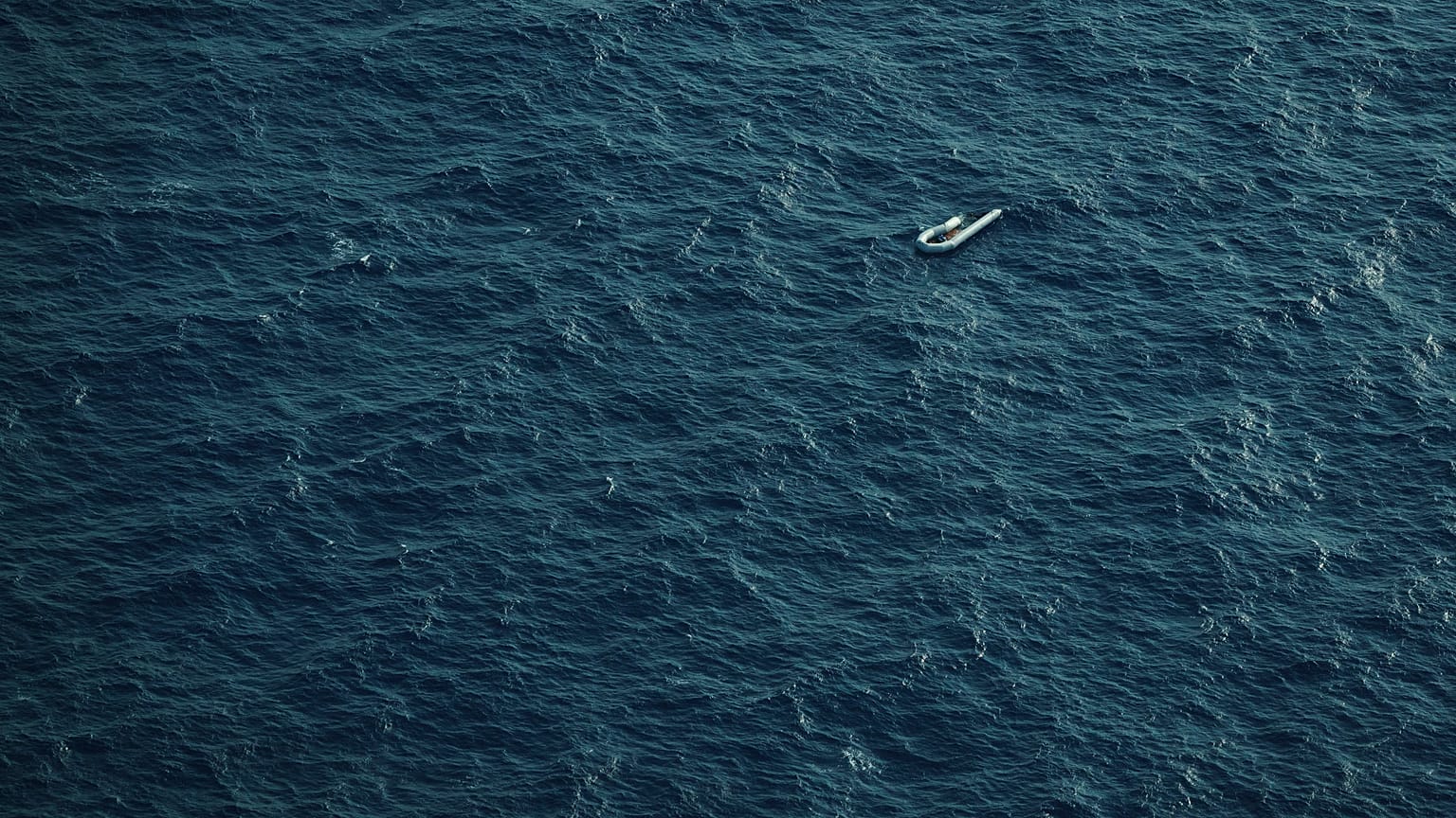 A partially deflated and empty rubber dinghy floats in the Mediterranean Sea between Libya and Italy.
