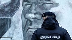 A police officer stands by a mural of former Bosnian Serb military chief Ratko Mladić in Belgrade, Serbia, Tuesday, Nov. 9, 2021.