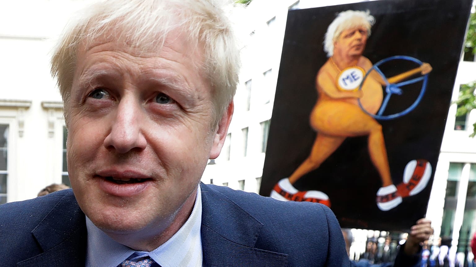 Boris Johnson walks past a satirical art work held up by artist Kaya Mar as he arrives to launch his leadership campaign, in London, Wednesday June 12, 2019