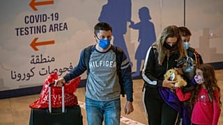 Travellers wearing protective face masks arrive at the Ben Gurion Airport near Tel Aviv, Israel, Sunday, Nov. 28, 2021. 