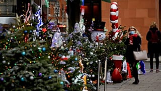 Egy nő nézelődik egy karácsonyi dekorációba öltöztetett mayfair-i borkereskedés előtt Londonban