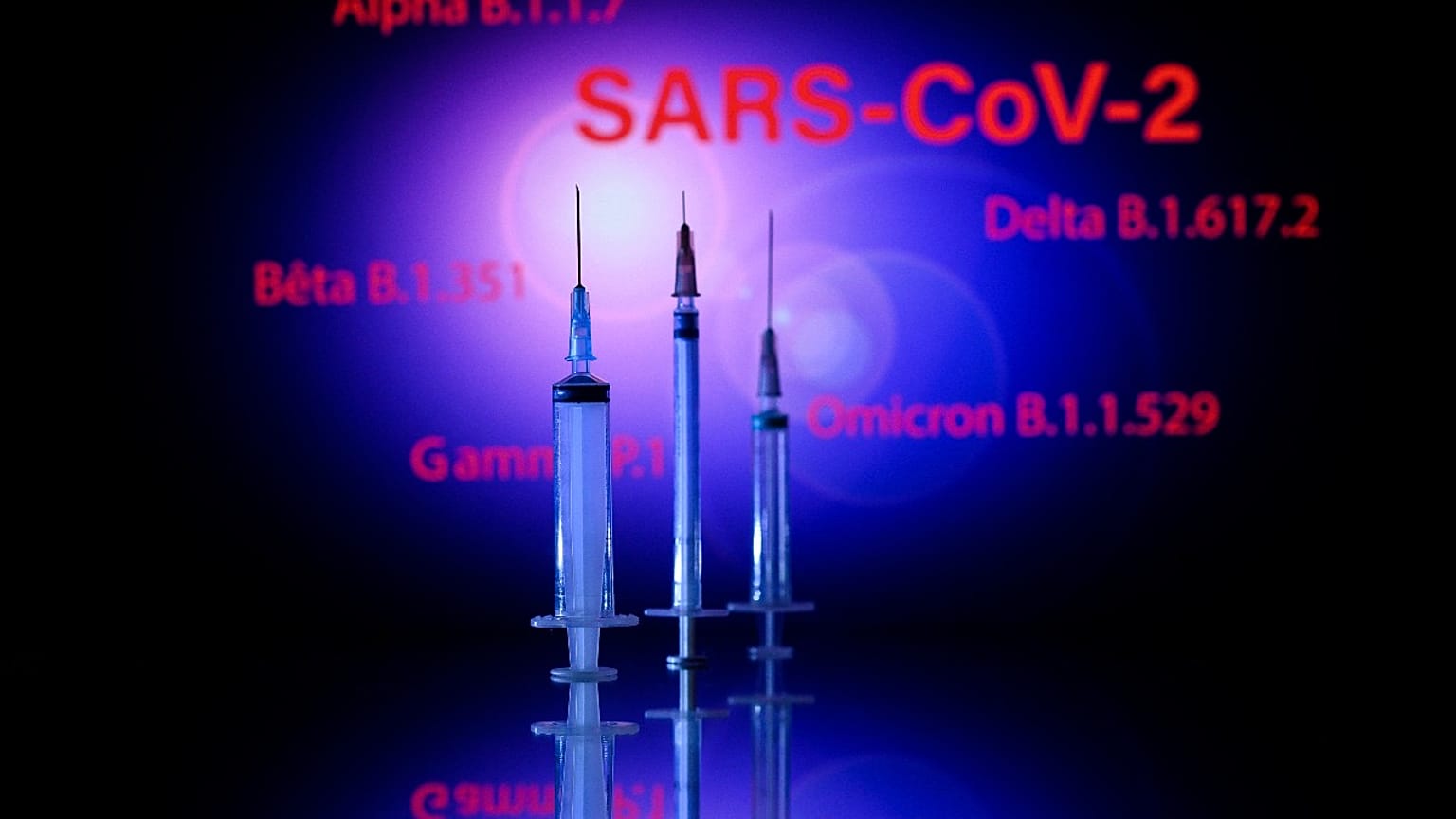 This photograph taken on December 2, 2021, shows a syringe and a screen displaying the SARS-Cov-2 mains variants : Alpha, Beta, Delta, Gamma and Omicron, in Toulouse.