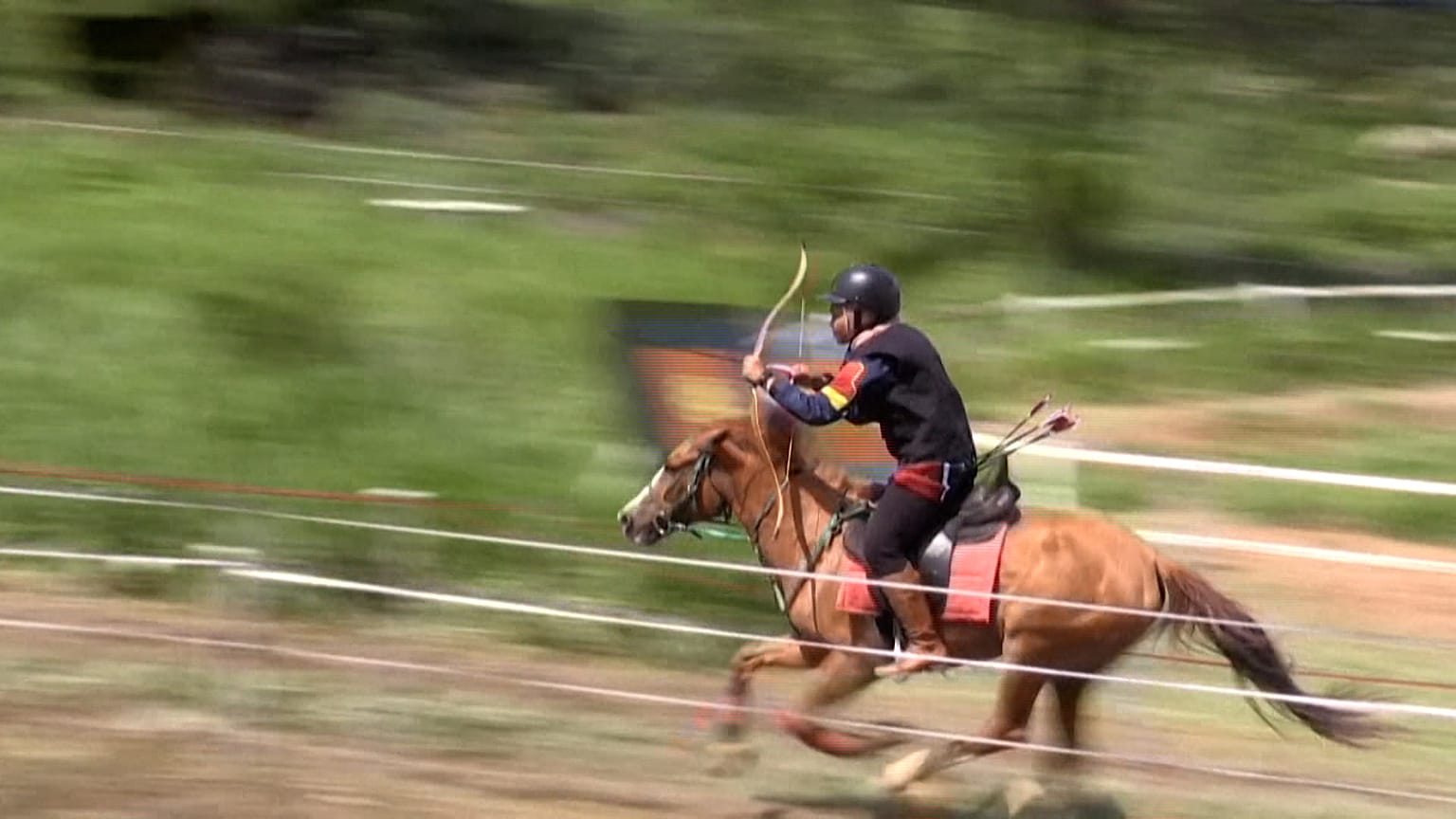 A rider shoots her arrows one-by-one at several targets down the track 