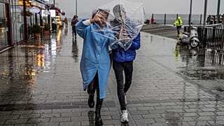 A couple shelters against a heavy rain with an umbrella during a stormy day in Istanbul.