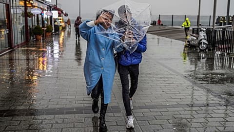 A couple shelters against a heavy rain with an umbrella during a stormy day in Istanbul.