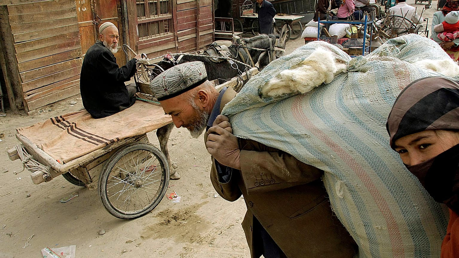 Doğu Türkistan'ın Hoten kentinde yün taşıyan Uygur adam ve kadın (arşiv) 