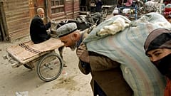 Doğu Türkistan'ın Hoten kentinde yün taşıyan Uygur adam ve kadın (arşiv) 