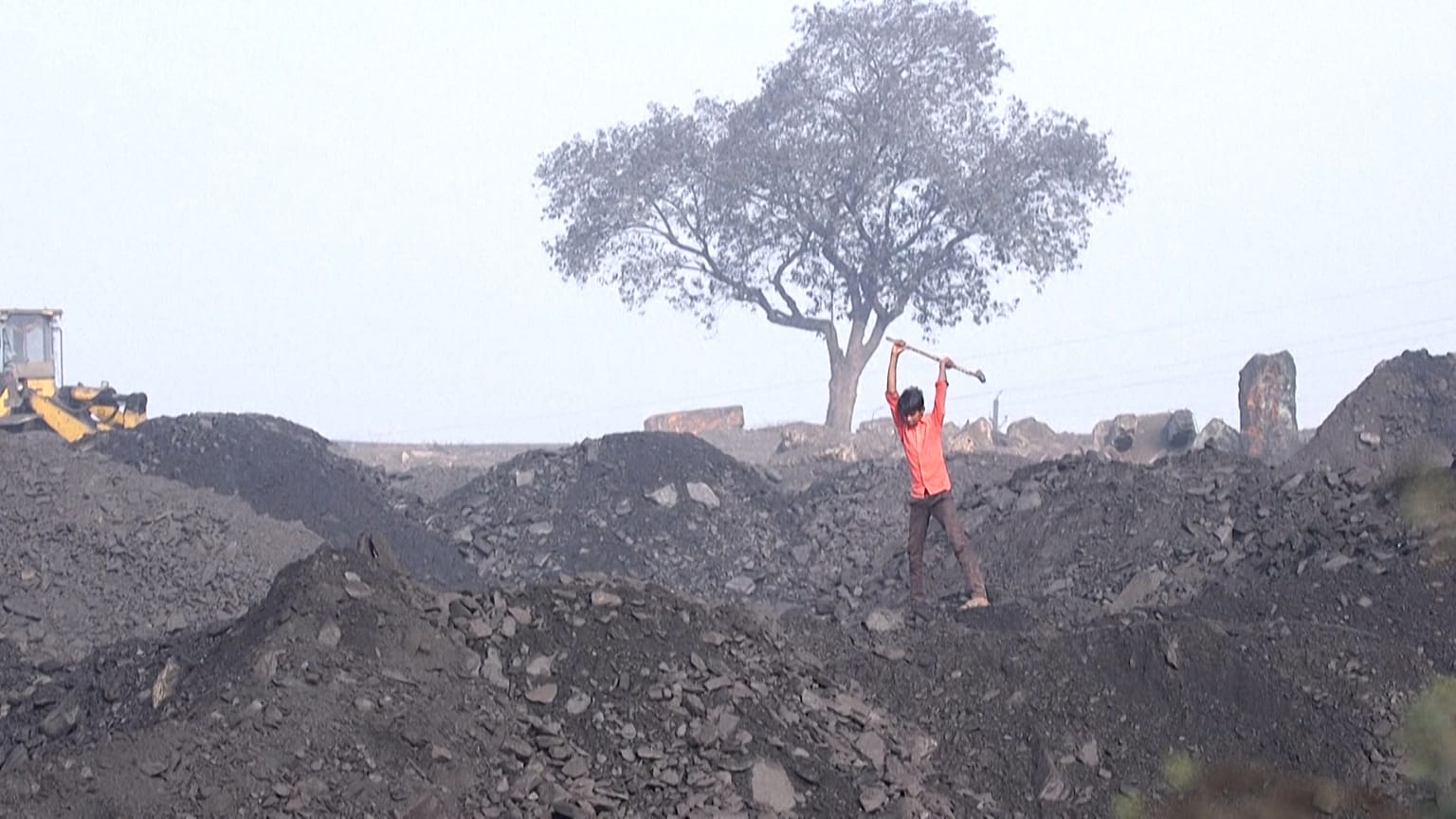Young boy breaks coal in a coalyard 