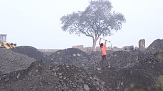Young boy breaks coal in a coalyard 