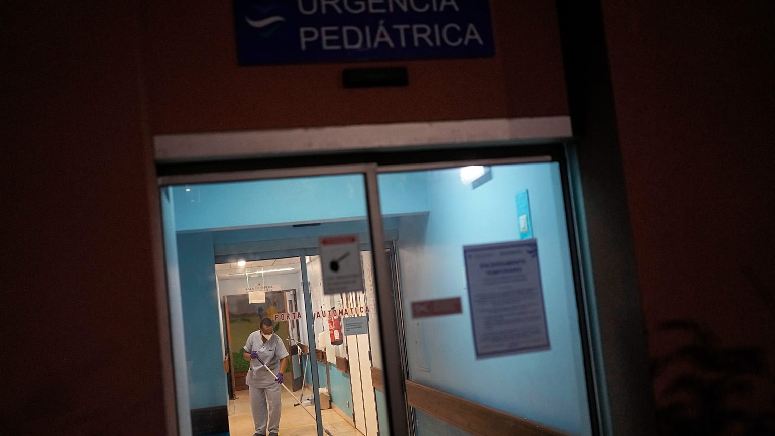 A worker wipes the floor by the pediatric emergency entrance at the Hospital Garcia de Orta in Almada, south of Lisbon, Tuesday, Nov. 30, 2021. 