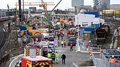 Firefighters, police officers and railway employees stand on a railway site in Munich.