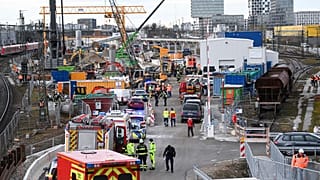 Firefighters, police officers and railway employees stand on a railway site in Munich.