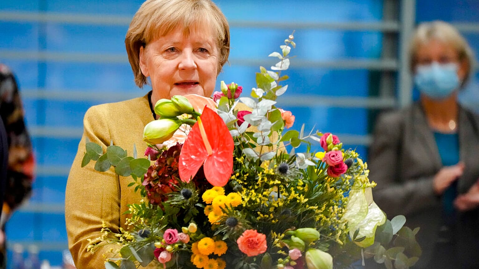 La canciller alemana Angela Merkel sostiene un ramo de flores de manos del vicecanciller y ministro de Economía Olaf Scholz, 24/11/2021, Berlín, Alemania