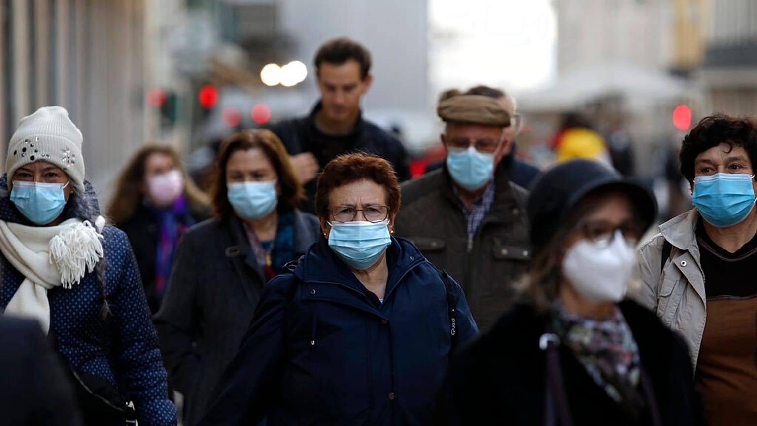 People wearing face masks to curb the spread of COVID-19 walk in downtown Lisbon, Monday, Nov. 29, 2021. 