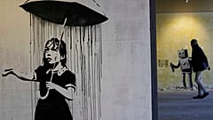 "The Umbrella girl" a reproduction of a mural by British artist Banksy is seen at an exhibition at the Milano Centrale main railway station in Milan, on Dec. 2, 2021.