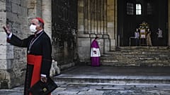 A priest wearing a face mask waits for Patriarch Manuel Clemente (L) before celebrating the first Sunday mass at Lisbon Cathedral on May 31, 2020.