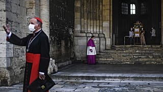 A priest wearing a face mask waits for Patriarch Manuel Clemente (L) before celebrating the first Sunday mass at Lisbon Cathedral on May 31, 2020.