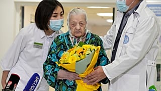 Doctors greet 101-year-old patient Pelageya Poyarkova with flowers as she leaves a COVID recovery ward, Federal Center for Brain and Neurotechnology, Moscow, Dec. 3, 2021.