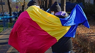 Román zászlóval sétál egy pár Bukarestben 2021. december 1.én 