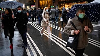 Pedestrians wear masks to prevent the spread of the COVID-19 as they walk past a store illuminated as part of Christmas lightings, in Paris, Monday, Dec. 6, 2021.