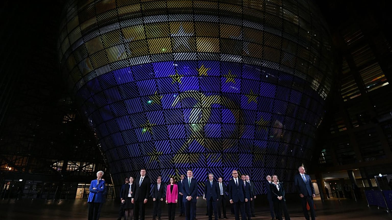 A presidente do BCE, Christine Lagarde, e os ministros das Finanças da Zona Euro em frente a um painel que assinala os 20 anos do Euro