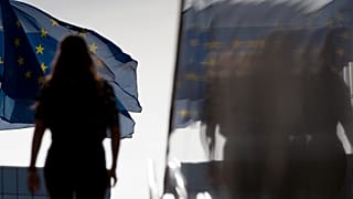 Une femme marche vers des drapeaux de l'Union européenne à Bruxelles.