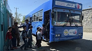 In this photograph taken on April 4, 2018, Afghan children board a mobile library bus in Kabul. 