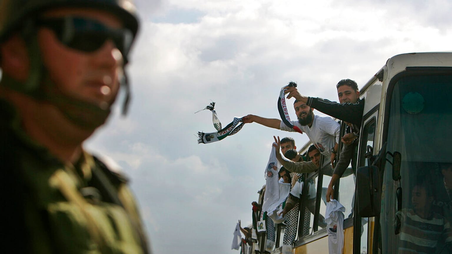 جندي إسرائيلي يشاهد أسرى فلسطينيين أطلق سراحهم يحتفلون بعد عبورهم حاجز بيتونيا العسكري إلى مدينة رام الله بالضفة الغربية، الإثنين 15 ديسمبر 2008