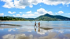 Tourists walk on a beach on the Thai island of Phuket on November 1, 2021, as Thailand welcomes the first group of tourists fully vaccinated against the Covid-19 coronavirus.