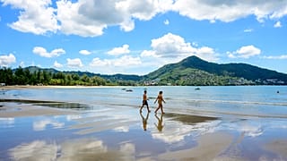 Tourists walk on a beach on the Thai island of Phuket on November 1, 2021, as Thailand welcomes the first group of tourists fully vaccinated against the Covid-19 coronavirus.