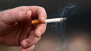 A man holds a lit cigarette.