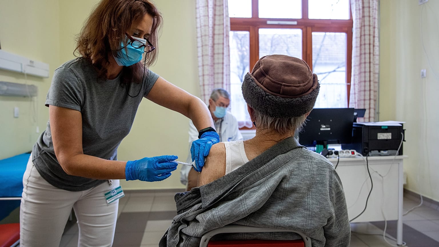Szatmáriné Schell Anikó asszisztens beolt egy férfit a német-amerikai fejlesztésű Pfizer-BioNTech koronavírus elleni oltóanyag harmadik, emlékeztető adagjával