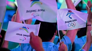 مشاركون يلوحون بالأعلام التي تحمل شعارات أولمبياد بكين الشتوية والألعاب الأولمبية للمعاقين 2022. 2021/09/17