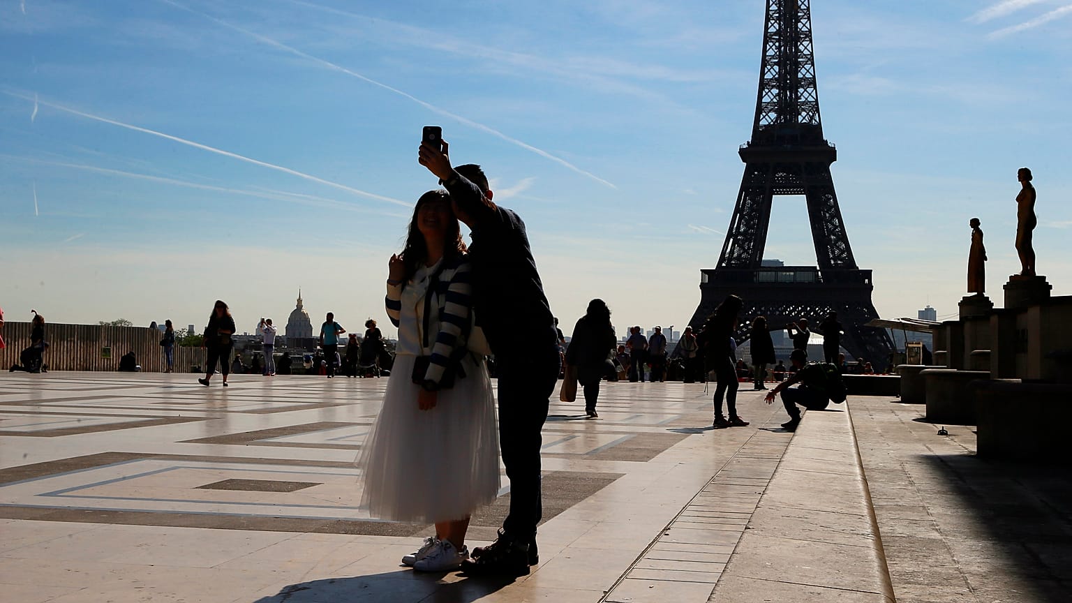 Tourists take a selfie on Trocadero with the Eiffel Tower in background on a sunny day in Paris