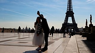 Tourists take a selfie on Trocadero with the Eiffel Tower in background on a sunny day in Paris