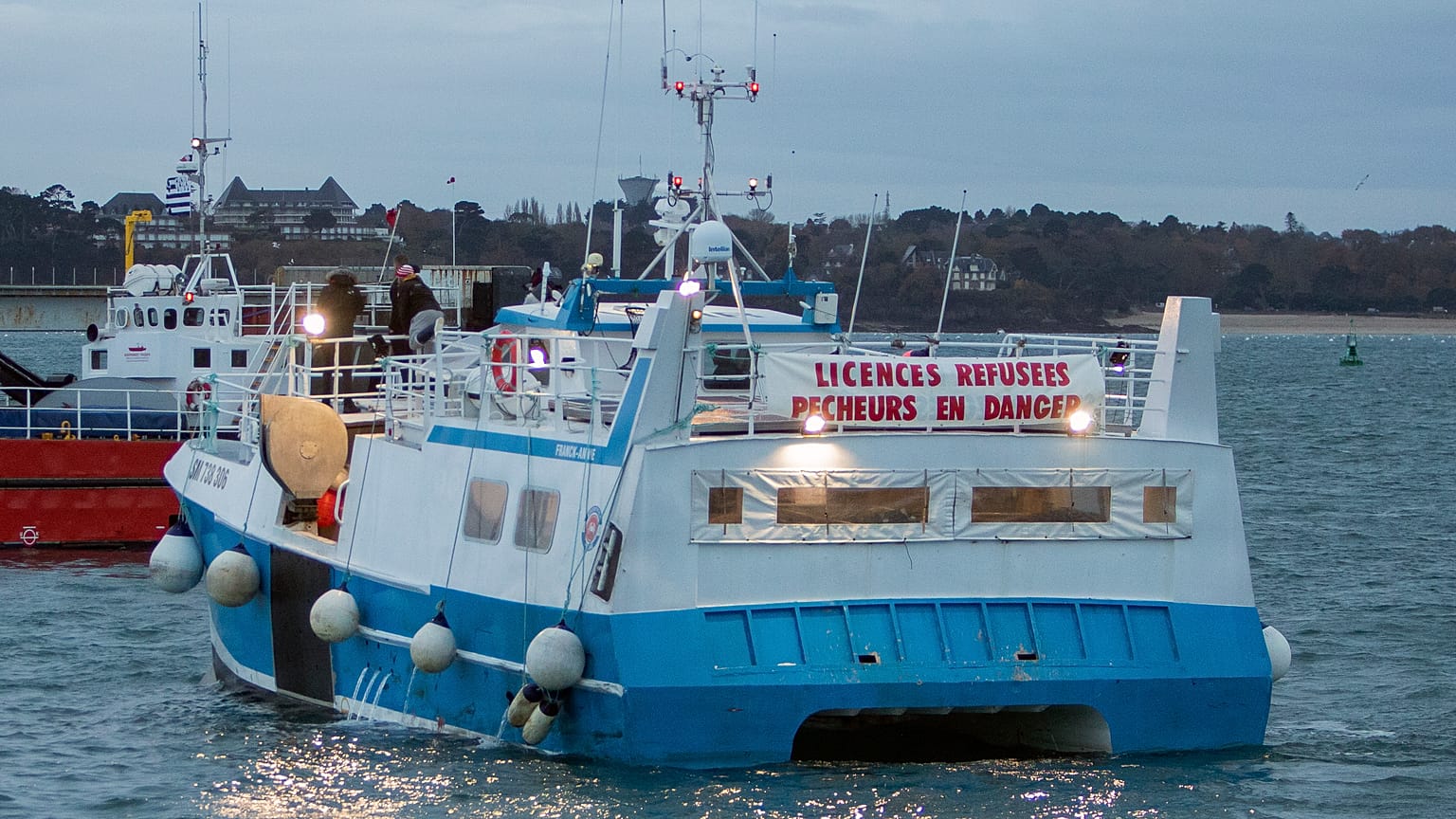 A banner reading "licenses refused. Fishermen in danger" is set on a French fishing boat during a blockage of the entrance to the port of Saint-Malo, France, Nov. 26, 2021.