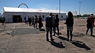 People wait in line at a COVID-19 vaccination centre, near Tor Vergata hospital in Rome.