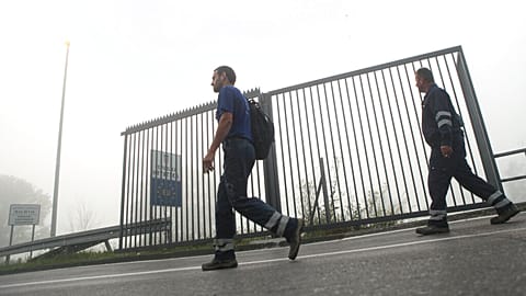 FILE: Two men walk past a section of the fence along the border between Croatia and Bosnia near the village of Maljevac, Croatia, Tuesday June 11, 2019.