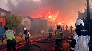Bomberos trabajan en un incendio forestal que afectó a decenas de casas en la comuna, 9/12/2021. Castro, Chile