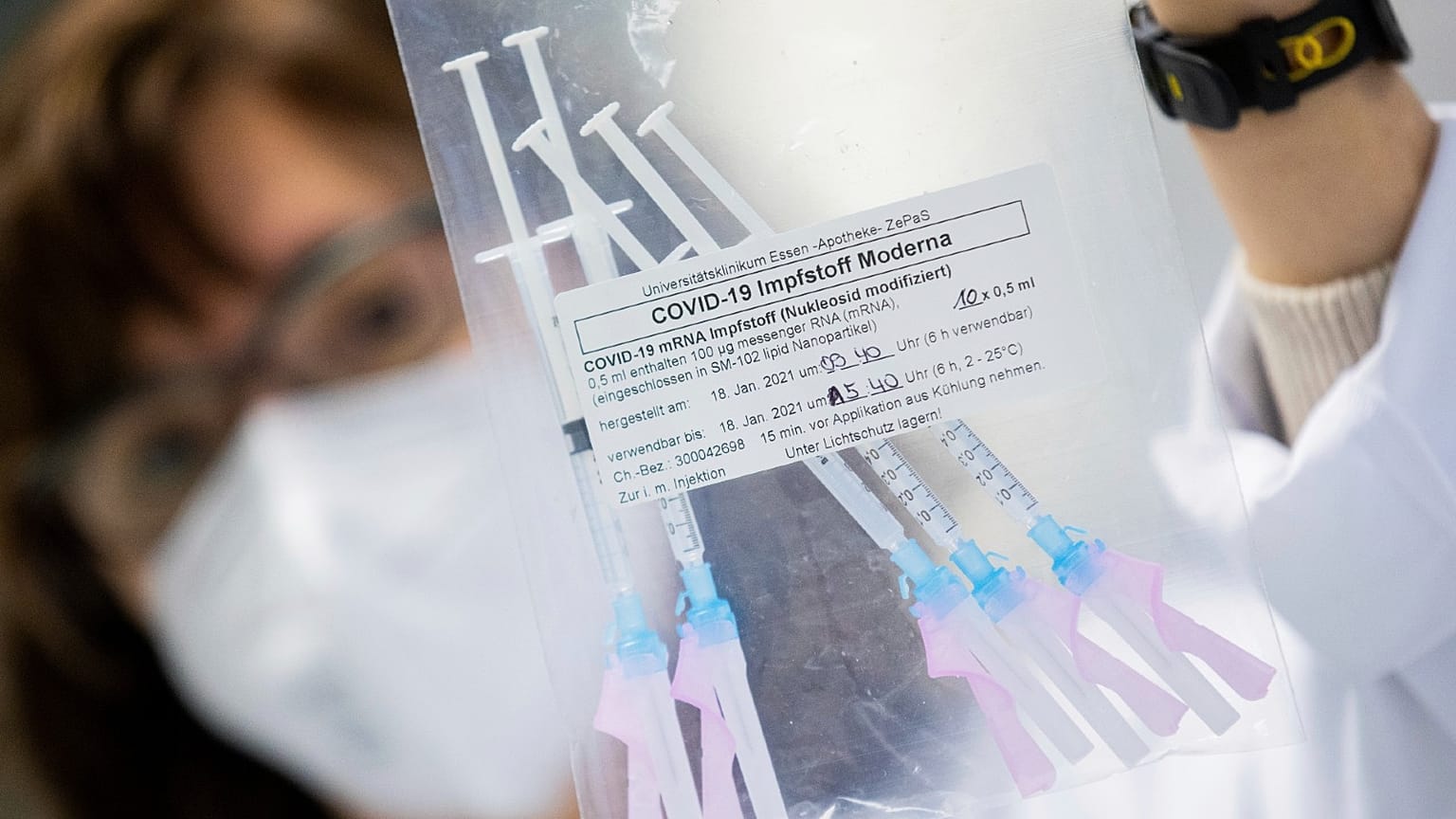 A healthcare worker shows a bag of syringes containing the Moderna new coronavirus vaccine immediately before a vaccination at the University Hospital in Essen, Germany