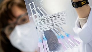 A healthcare worker shows a bag of syringes containing the Moderna new coronavirus vaccine immediately before a vaccination at the University Hospital in Essen, Germany