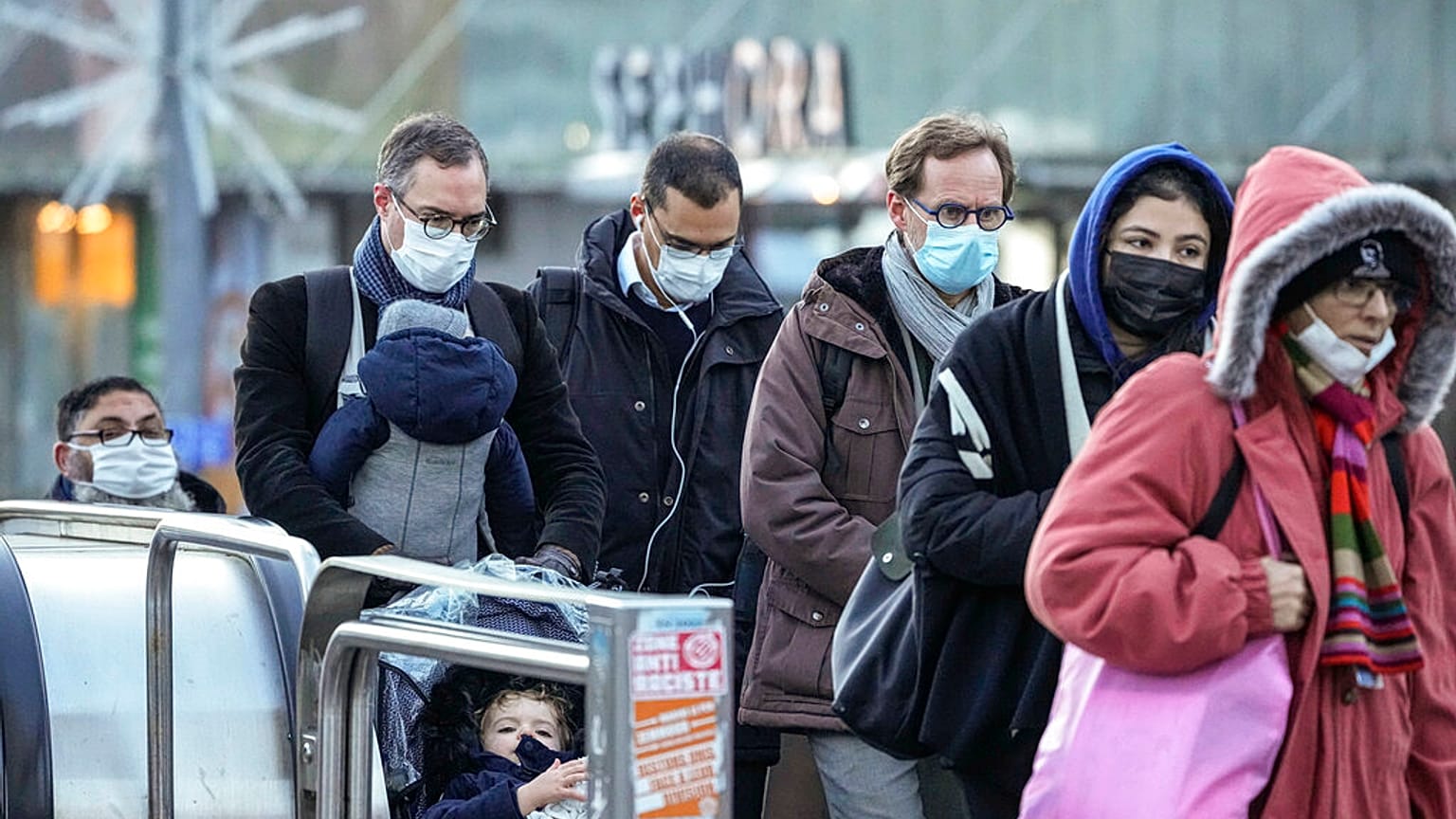 Commuters wearing face masks to protect against COVID-19 ride an escalator at La Defense business district in Paris on Wednesday, December 8