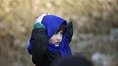 Afganistan'ın başkenti Kabil'de bir yardım kuruluşu tarafından dağıtılan gıda yardımını alan bir kız çocuğu babasını beklerken