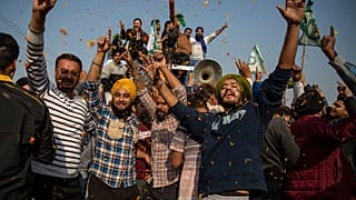 Indian farmers are showered with flower petals as they dance while leaving the protest site in Singhu, on the outskirts of New Delhi, India, Saturday, Dec. 11, 2021.
